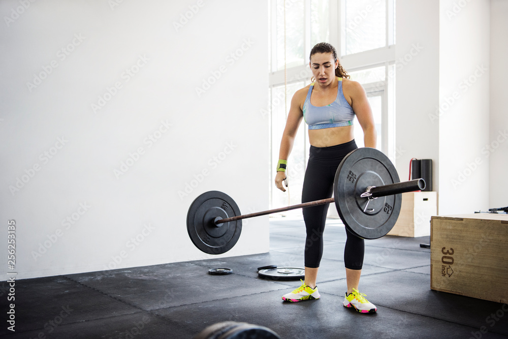 Female athlete throwing barbell in gym Female athlete throwing barbell in gym