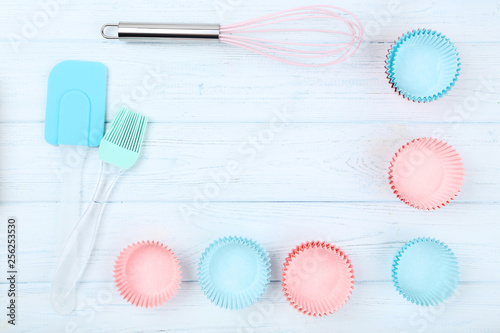 Cupcake cases with kitchen utensils on wooden table