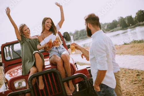 Young people drinking and having fun by car outdoor at hot summer day © BGStock72