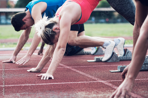 Athletes poised at starting blocks on track photo