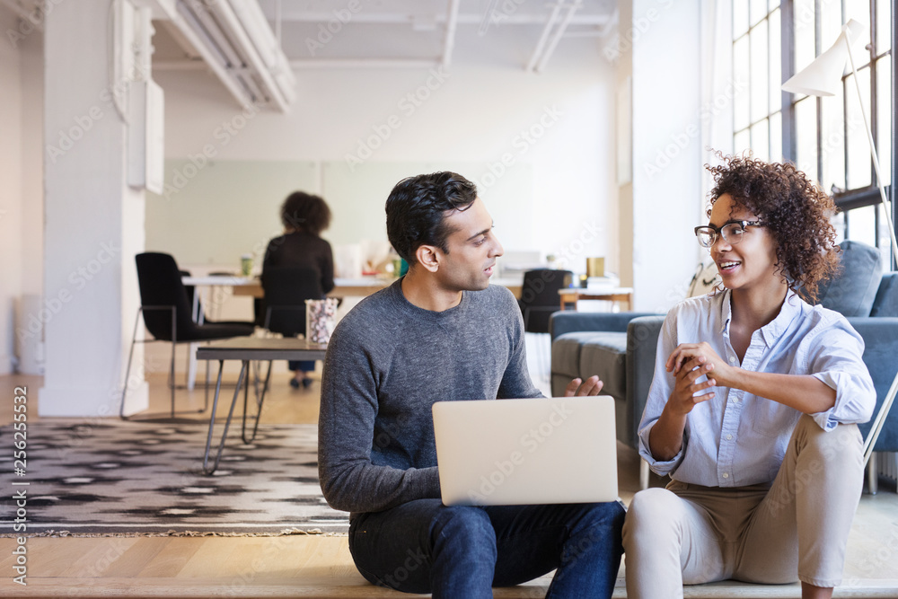 Business people talking while using laptop in office