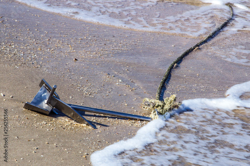 Photography Metal anchor with a tied rope on the sand