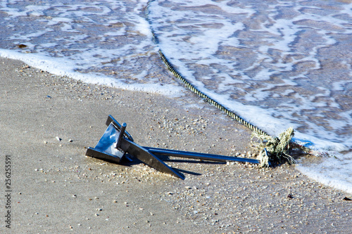 Metal anchor with a tied rope on the sand