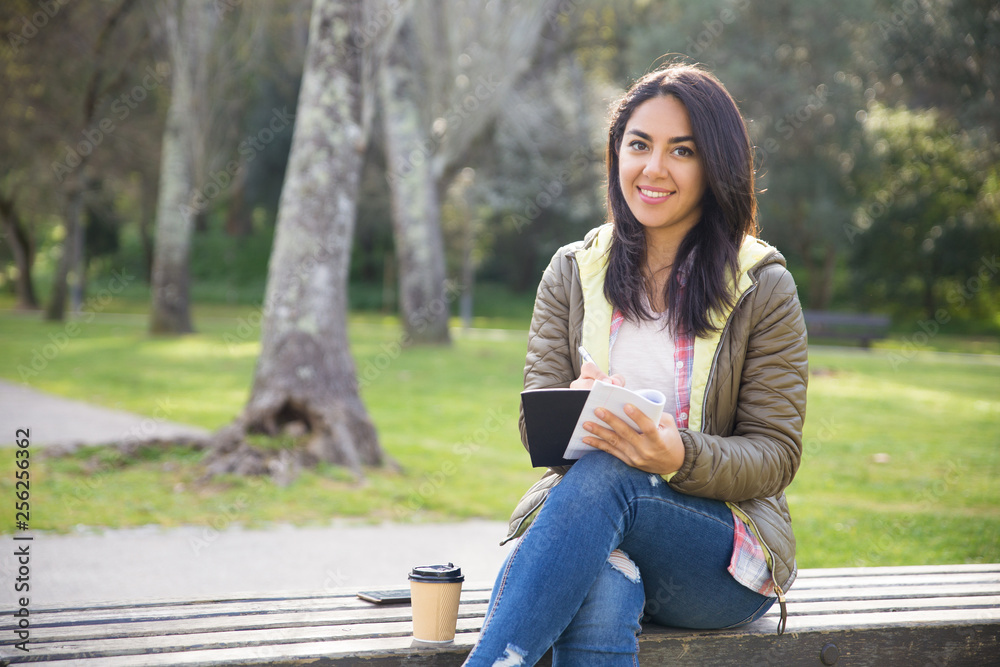 Obraz premium Cheerful mixed race girl planning day while sitting on bench