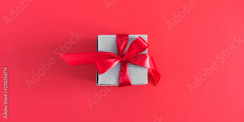 Gift with red satin bow on red background. Christmas. Wedding. Birthday. Happy womens day. Mothers Day. Valentine's Day. Flat lay, top view, copy space, banner  © prime1001