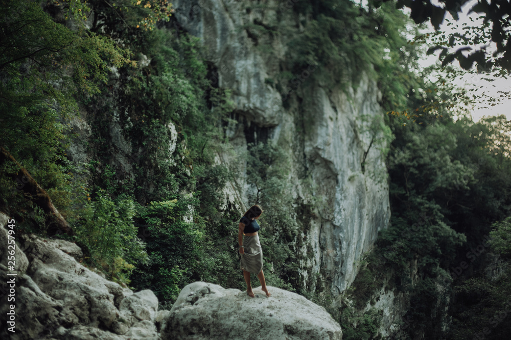 Young and sexy woman sit on rock wearing swimsuit on the beautiful waterfall in the jungle beside cliff Young and sexy woman sit on rock wearing swimsuit on the beautiful waterfall in the jungle beside cliff