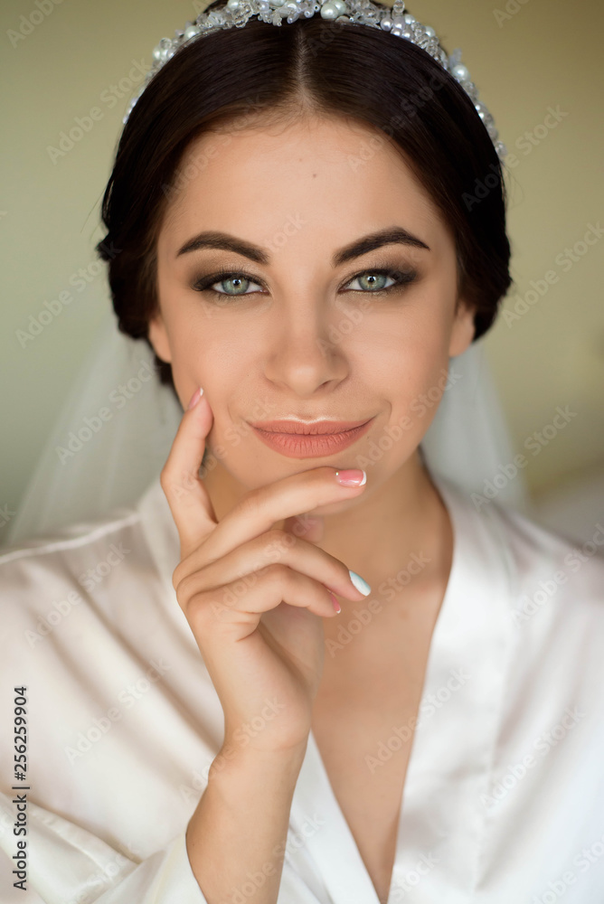 Portrait of beautiful bride with fashion veil posing on bed at wedding morning. Makeup. Brunette girl. Wedding veil.