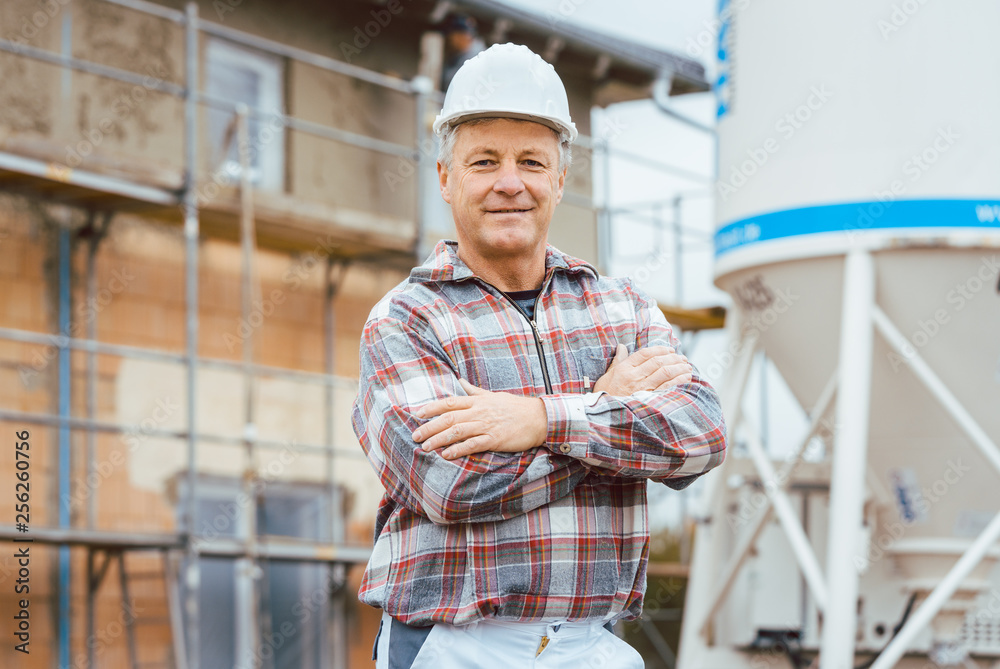 Obraz premium Proud plasterer standing in front of scaffold on construction site