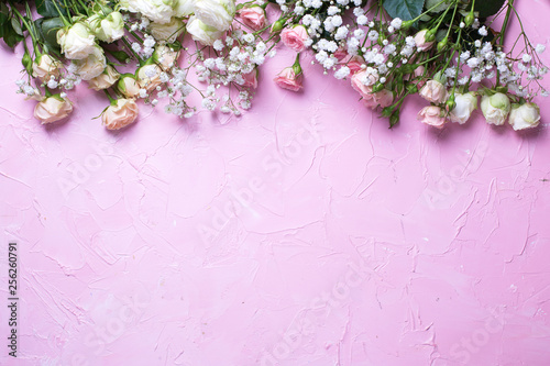 Border from fresh white gypsofila and white rose flowers on  pink textured background. photo
