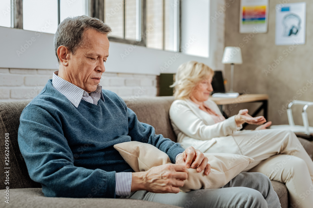 Silent short-haired man sitting on couch with a pillow Silent short-haired man sitting on couch with a pillow