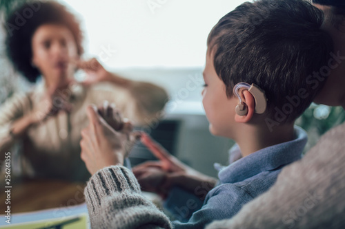 Smiling deaf boy learning sign language. Selective focus. photo