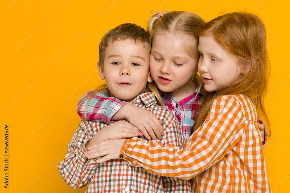 two little girls and boy on yellow background. cute children. friendship two little girls and boy on yellow background. cute children. friendship