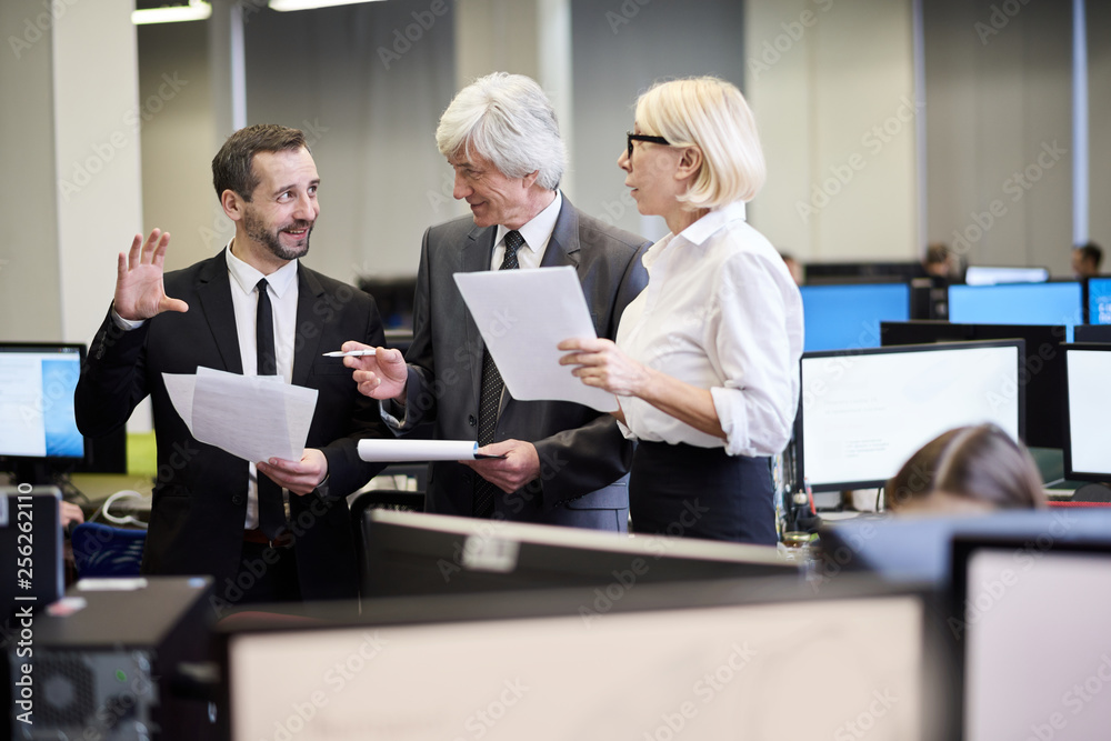 Group of cheerful business people discussing documents standing in office, copy space Group of cheerful business people discussing documents standing in office, copy space