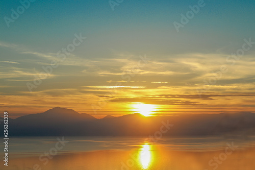 Dramatic sunset reflected in the water over the gulf of Corinth on mainland Greece headed up the mountains toward Delphi from the west