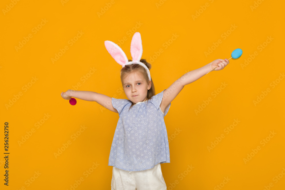Portrait of cute little child girl with Easter bunny ears holding colorful eggs on yellow background. Happy easter Portrait of cute little child girl with Easter bunny ears holding colorful eggs on yellow background. Happy easter