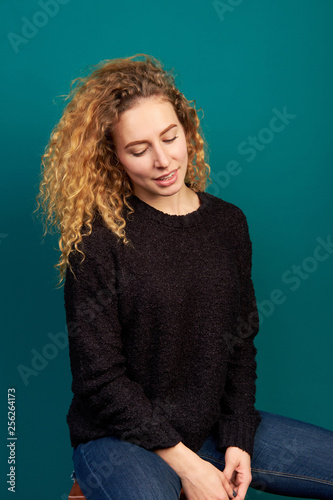 Attractive young curly redhead girl dressed in black sweater and jeans