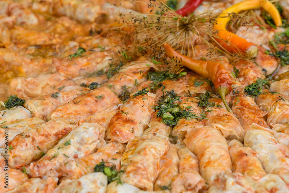 Close up of a freshly cooked large portion of sarmale, traditional Romanian cabbage rolls, with hot pepper and dill in display at a food market