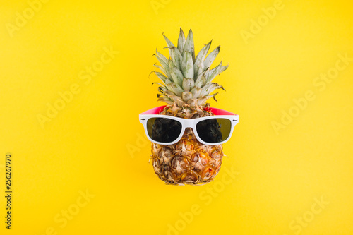 Summer concept. Cute and funny pineapple with sunglasses on yellow background.