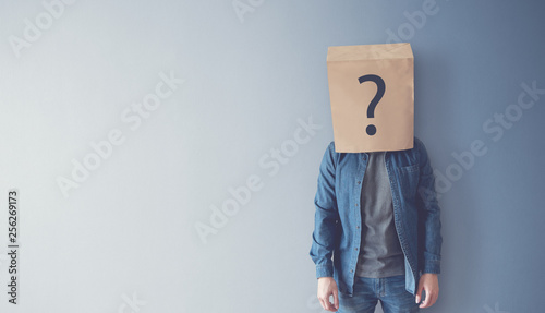 Man has Confused, Thinking, Question Mark Icon on Paper Bag, copy space. photo
