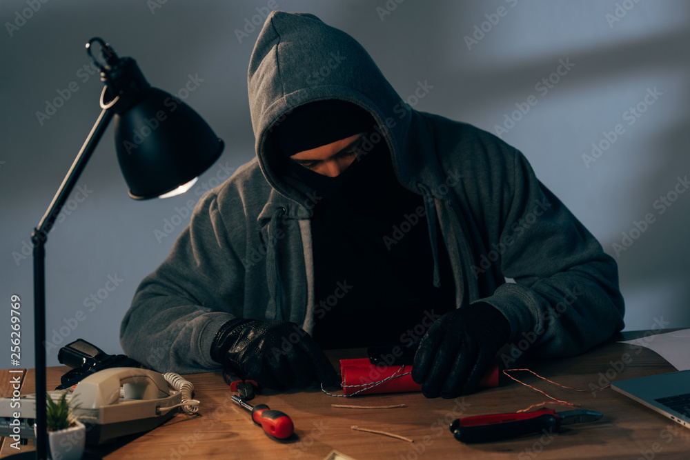 Concentrated terrorist in leather gloves making bomb in room Concentrated terrorist in leather gloves making bomb in room