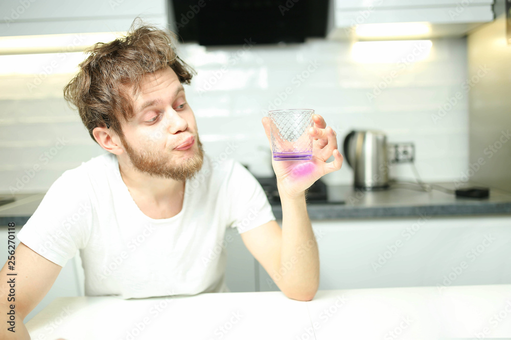 bearded male alcoholic man drinks alcohol from a glass at home in the kitchen. The concept of a hangover and alcoholism bearded male alcoholic man drinks alcohol from a glass at home in the kitchen. The concept of a hangover and alcoholism
