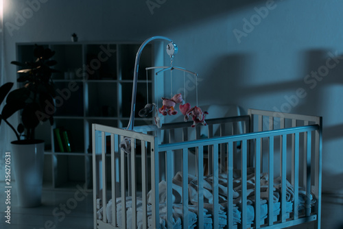 Photography Cupboard, crib and mobile with toys in dark nursery