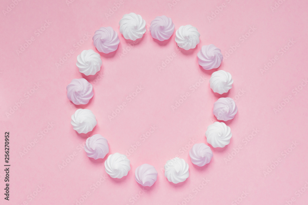 Top view of white and pink twisted meringues  on pink background. French dessert prepared from whipped with sugar and baked egg whites. Greeting card with copy space