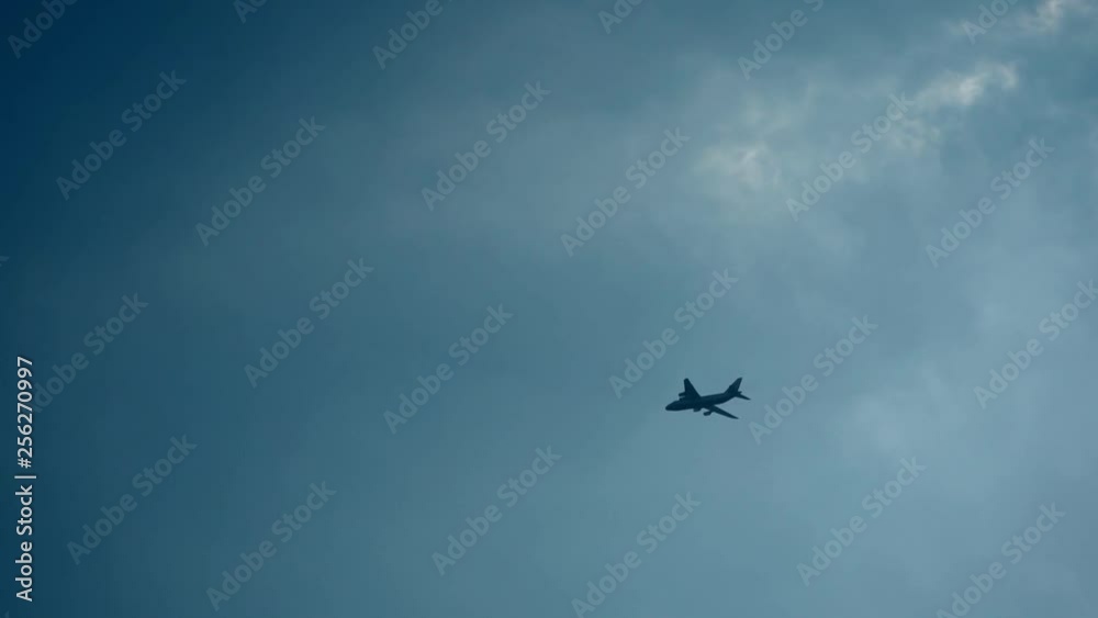 Silhouette of a big passenger airplane in a blue cloudy dramatic sky, which is flying away. Silhouette of a big passenger airplane in a blue cloudy dramatic sky, which is flying away.