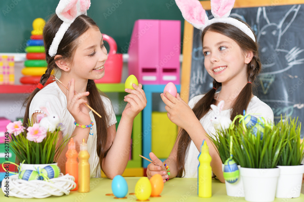 Portrait of cute twins wearing rabbit ears decorating Easter eggs Portrait of cute twins wearing rabbit ears decorating Easter eggs