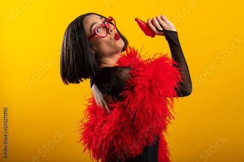 Beautiful Asian woman with vibrant red feather boa and heart shaped glasses, 
