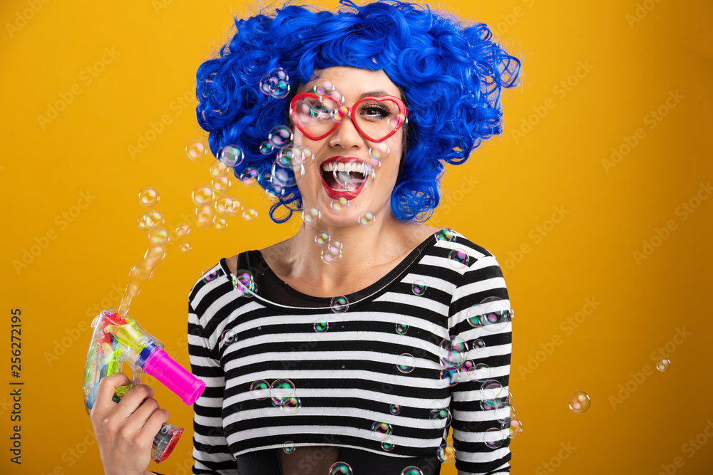 Fun woman playing with bubble machine wearing blue wig Fun woman playing with bubble machine wearing blue wig