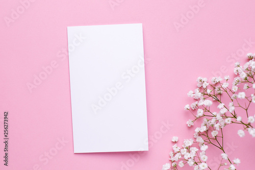 Present card with white flowers on pink pastel table top view and flat lay style. Fashion summer color.