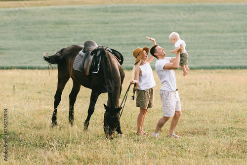 A young family have a fun in the field. Parents and child with a horse © jul14ka