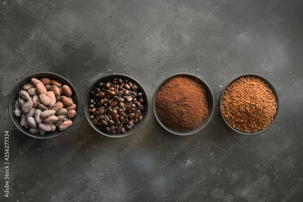 Concept of cocoa and coffee beans in bowls on dark.