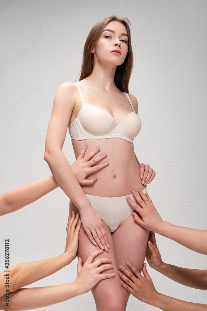 cropped view of female hands touching attractive girl isolated on grey, body positivity concept cropped view of female hands touching attractive girl isolated on grey, body positivity concept