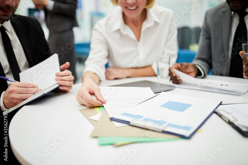 Closeup of unrecognizable businesswoman reading documents during meeting in office, copy space background
