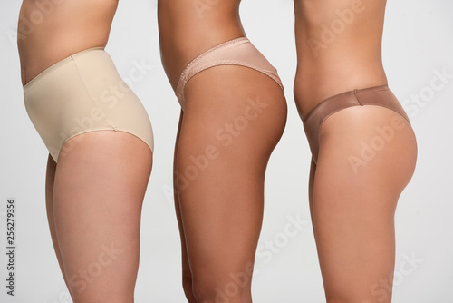 cropped view of three multiethnic woman in panties isolated on grey, body positivity concept
