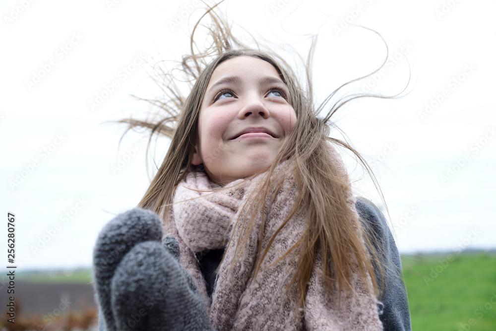 Portrait of smiling girl with blowing hair in winter looking up Portrait of smiling girl with blowing hair in winter looking up