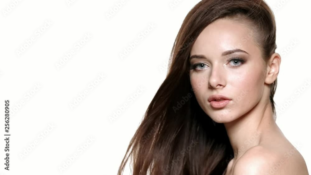 Beautiful young woman with long brown hair posing in front of the camera in the Studio. Beautiful young woman with long brown hair posing in front of the camera in the Studio.