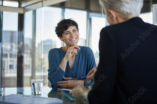 Two businesswomen talking at desk in office photo
