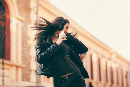 Young woman enjoys music on the street and dancing