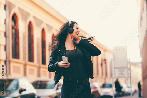 Young woman enjoys music on the street and dancing