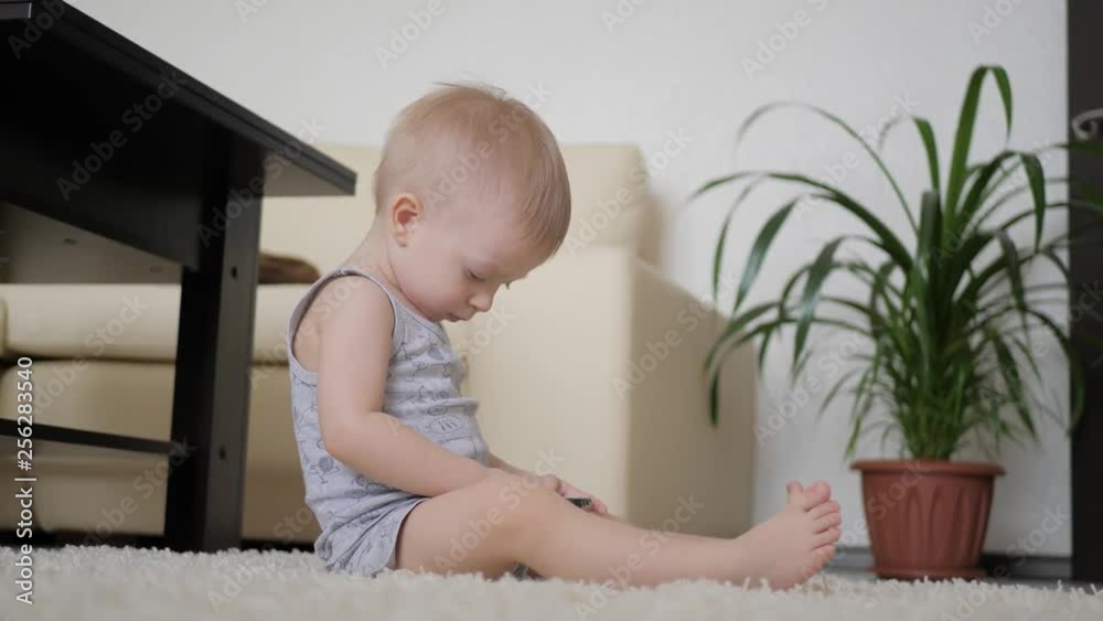 Little boy is watching cartoons on smartphone on the floor at home, lifestyle. Little boy is watching cartoons on smartphone on the floor at home, lifestyle.