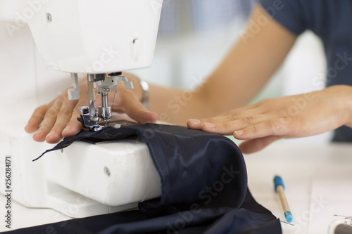Young fashion designer using sewing machine at her workshop
