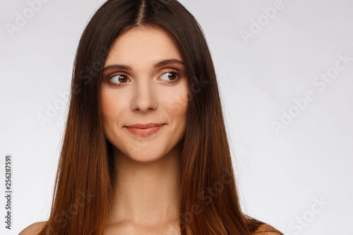 Portrait of a beautiful woman with straight long hair and interesting emotion. Light gray background