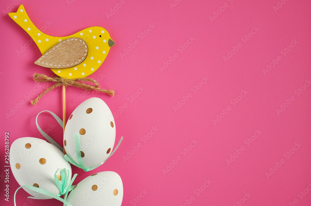 Easter eggs are white blue polka dots. Festive mood. Easter attributes. Easter decoration bird. Drawing on the eggs. Pink background