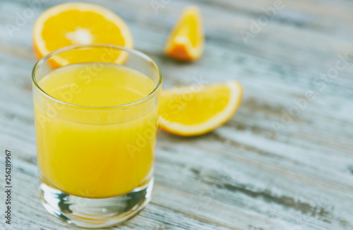 a glass of fresh orange juice with fresh citrus fruits on a light wooden table. horizontal view. citrus juice