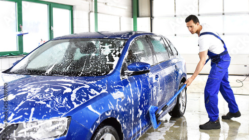 Cuadro en lienzo Car wash - employees of a car dealership clean a vehicle professionally