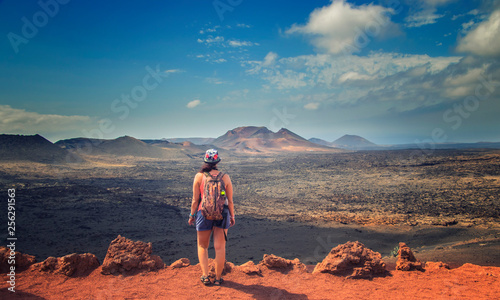 The tourist is standing on the edge of the rock and looks at the red mountains in the national park Timanfaya in Lanzarote photo