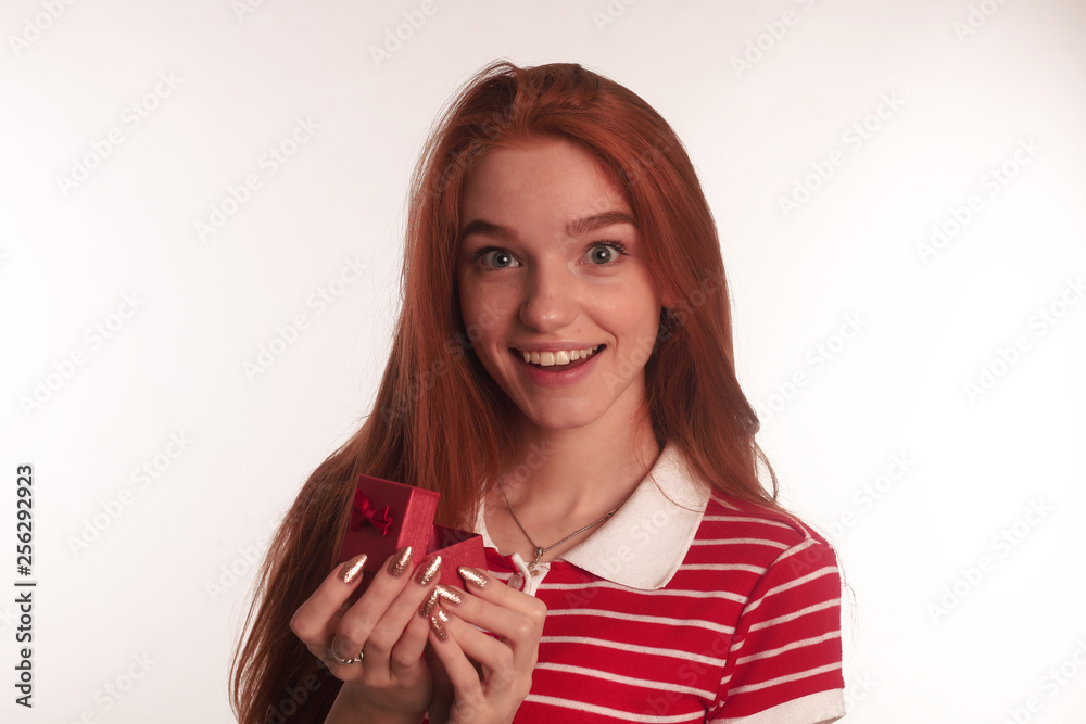 The portrait of an young redhead lady with a gift box in her hands isolated over white background posing The portrait of an young redhead lady with a gift box in her hands isolated over white background posing